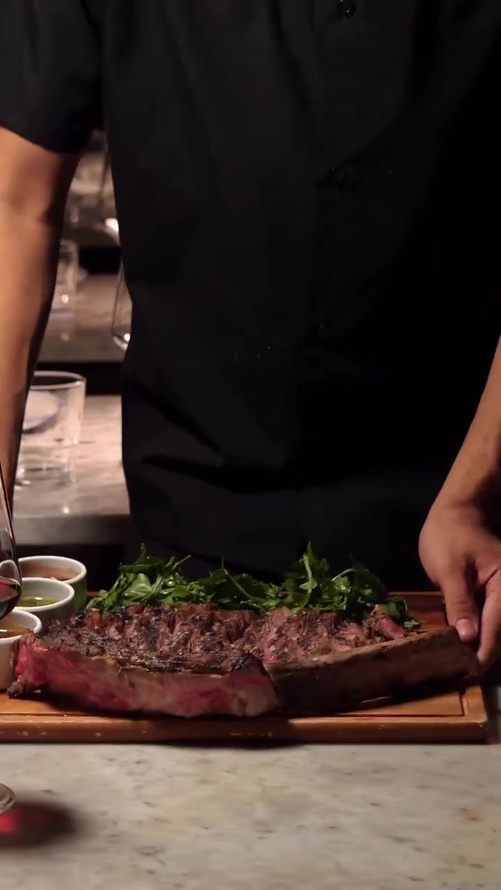Chargrilled steak sliced and plated tableside, fire-led cooking