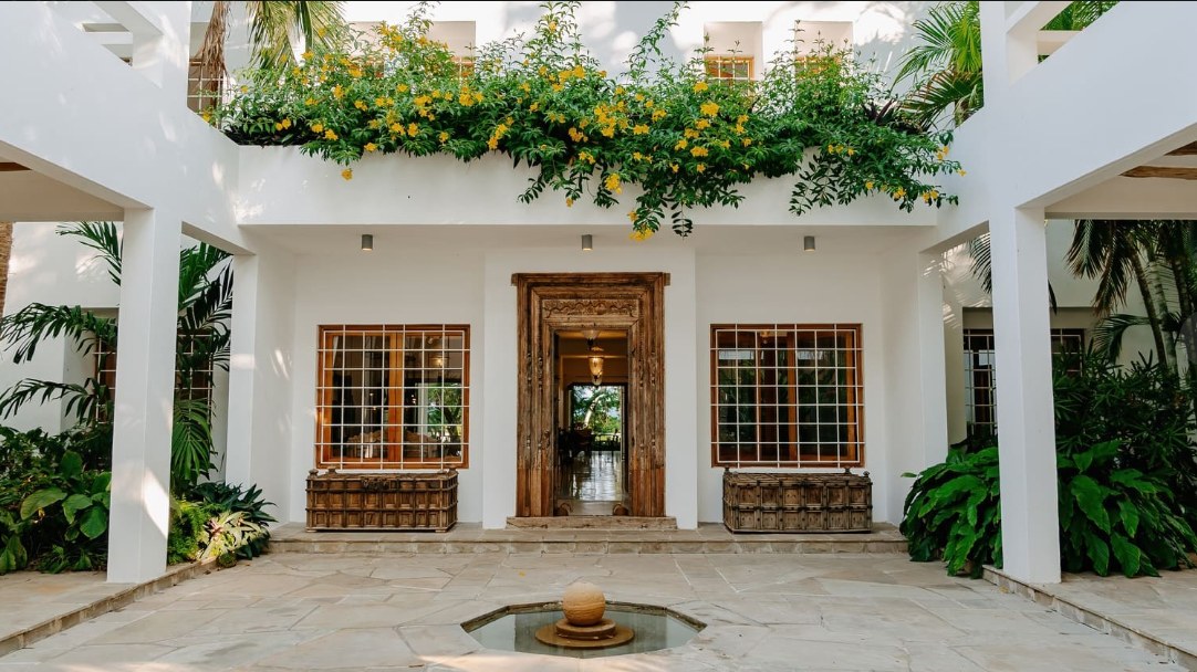 White-arched courtyard with carved Swahili door at Zuri