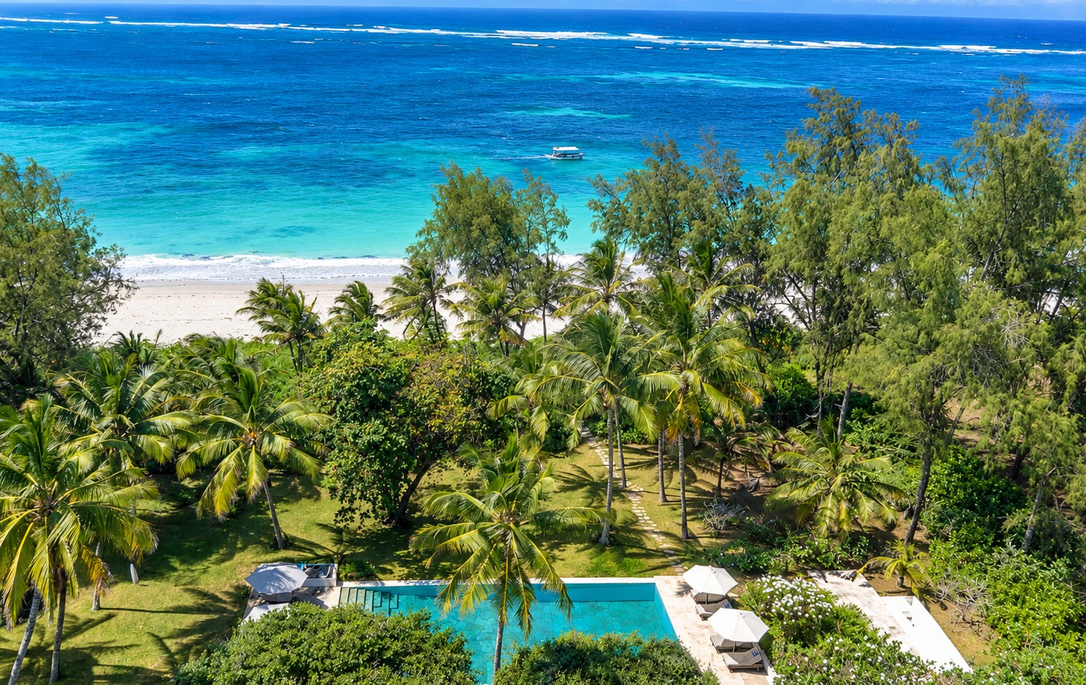 Aerial view of Zuri's palms, lawn and pool meeting the Indian Ocean at Garoda Beach